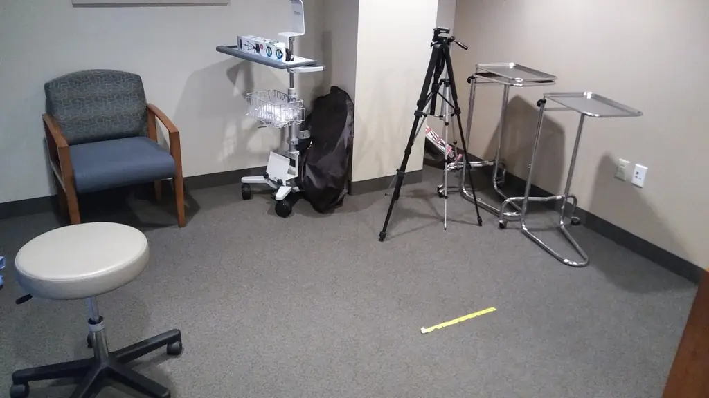 Clinical exam room with a stool, chair and instrument trays